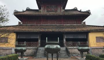 Traditional temple with a tiled roof and large pots in the foreground.