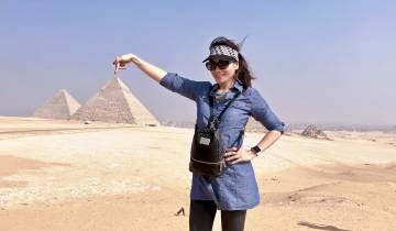 Woman pointing to the pyramids in the Giza desert.
