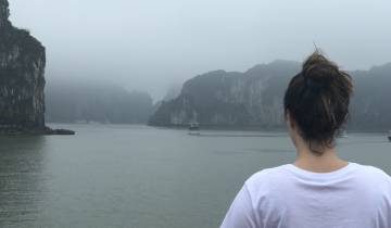 Person looking out over foggy bay with limestone formations.