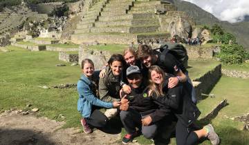 Group of people posing in front of historic stone terraces.