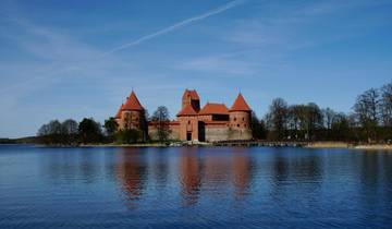 A medieval castle on an island surrounded by water under a blue sky.