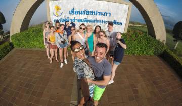 Group selfie at a scenic viewpoint with a sign in the background.