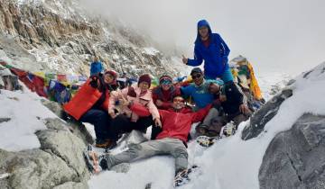 Group of people posing on a snowy mountain path.