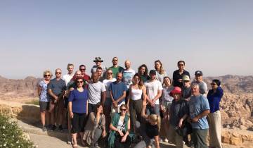 A large group of people posing against a desert landscape.
