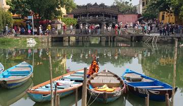 Colorful boats docked on a river with a bridge in the background.