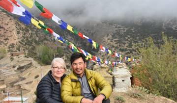 Two people sitting near prayer flags.