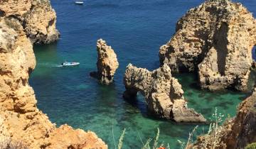 Rocky coastline with a small boat on turquoise water.