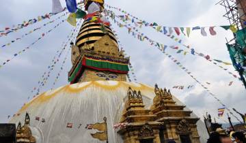 Majestic stupa with vivid prayer flags against the sky.