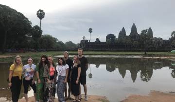 Group of people posing in front of Angkor Wat near reflection pool
