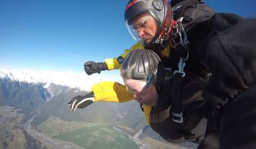 Skydivers in free fall over mountainous terrain.