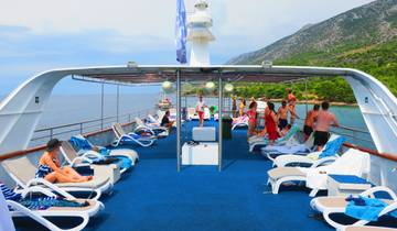 People lounging on a yacht deck with mountains in the background.