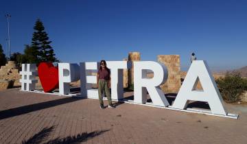 Person posing next to large Petra sign.