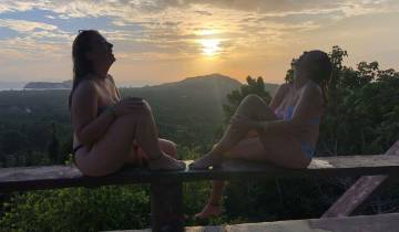 Two people sitting on a ledge during a beautiful sunset.