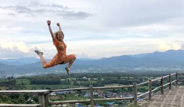 A person in mid-air with a scenic landscape in the background.