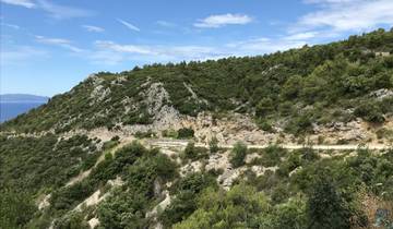 Winding road in a mountainous landscape with greenery.