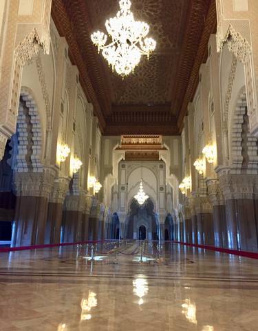 Intricate interior of a mosque with chandeliers and detailed arches.