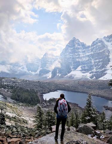 Person with a backpack overlooking a mountain with a lake.