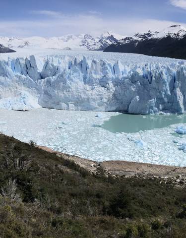 Panoramic view of Perito Moreno Glacier with surrounding mountains and lake.