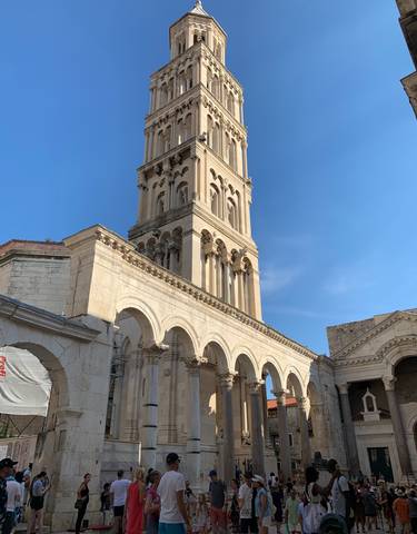 Historic stone tower and arch with tourists.