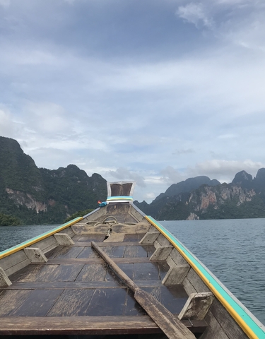 A traditional long-tail boat on a lake surrounded by mountains.