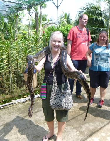 A woman holding a python in a garden setting.