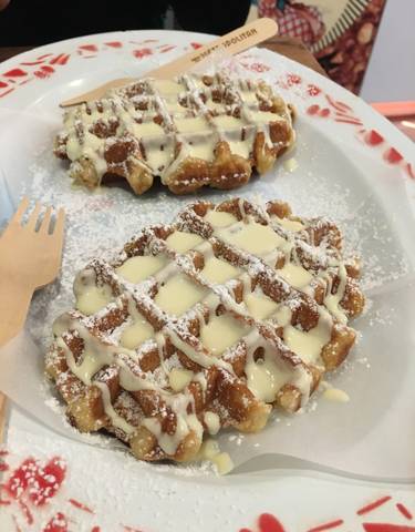 Close-up of waffles with powdered sugar and sauce.