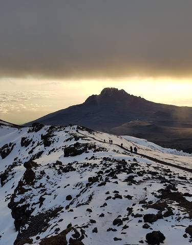 People hiking along a snowy mountain ridge.