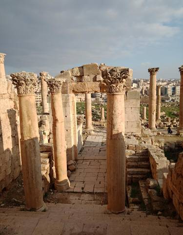 Ancient columns of Jerash with cityscape in the background.