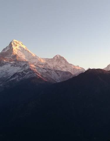 Mountain landscape at sunrise with peaks illuminated by the sun.