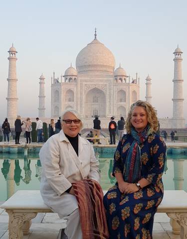 Two women smiling in front of the Taj Mahal.