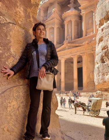 A person posing in front of the ancient Treasury in Petra.
