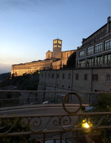 Large building with lights on at dusk overlooking a town.