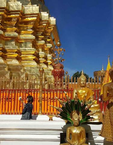 Golden statues and a temple complex under a blue sky.