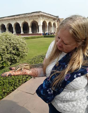A woman with henna on her hand holding a small animal.