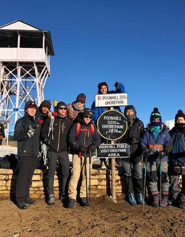 Group of hikers with signpost at Poon Hill in the snow.