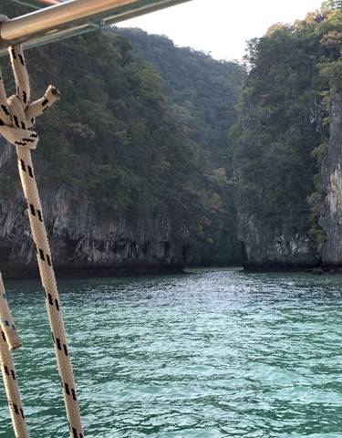 A boat sailing through a narrow passage between limestone cliffs.
