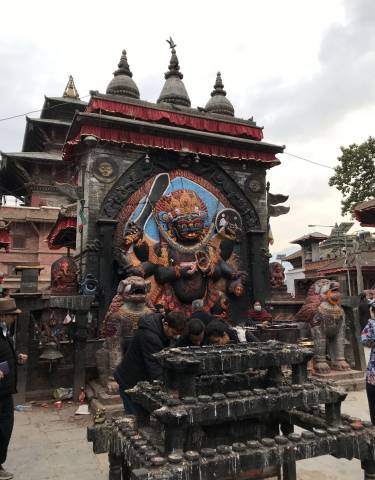 Vibrant Hindu temple with intricate deity sculpture and visitors.