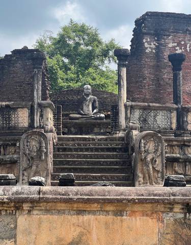 Ancient ruins with a Buddha statue in a meditation pose.