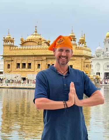 Man posing in front of a golden temple.