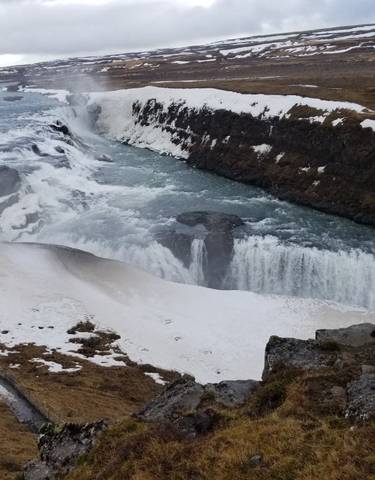 Frozen waterfall surrounded by icy landscape, Iceland.