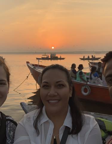 Group of people on a boat at sunset with other boats in the background.