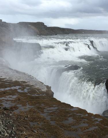 Powerful waterfall with mist and cliffs.