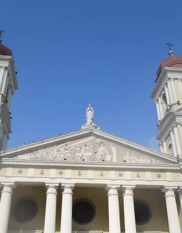 Cathedral facade with large columns under a bright sky.
