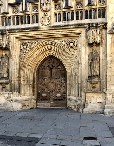 Ornate wooden door flanked by two statues, detailed carvings visible.