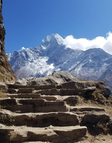 Rocky steps leading up to a large mountain covered in snow.