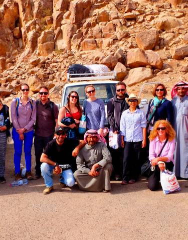 A group of people posing in front of rugged rocky scenery.