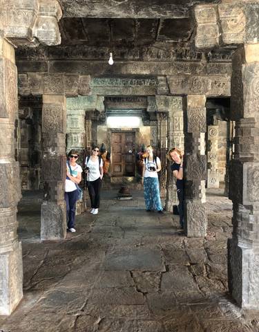 Tourists posing inside an ancient temple with ornate pillars.