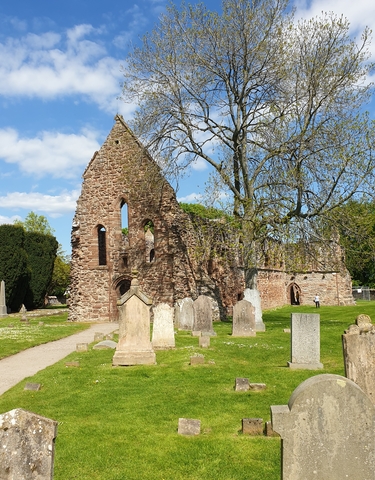 Ancient ruins with arched windows and gravestones.
