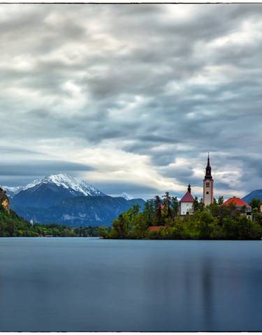 Wide view of Lake Bled with a church on the island and mountains in the background.