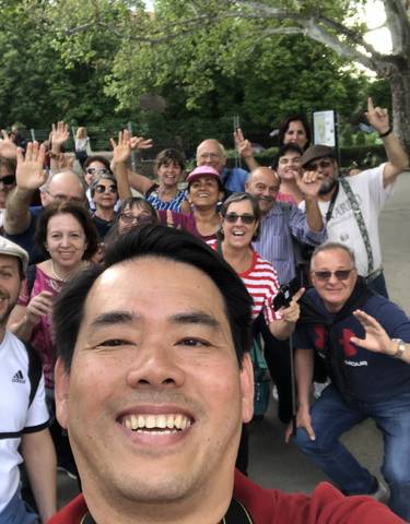 Large group of people smiling for a selfie in an outdoor setting.